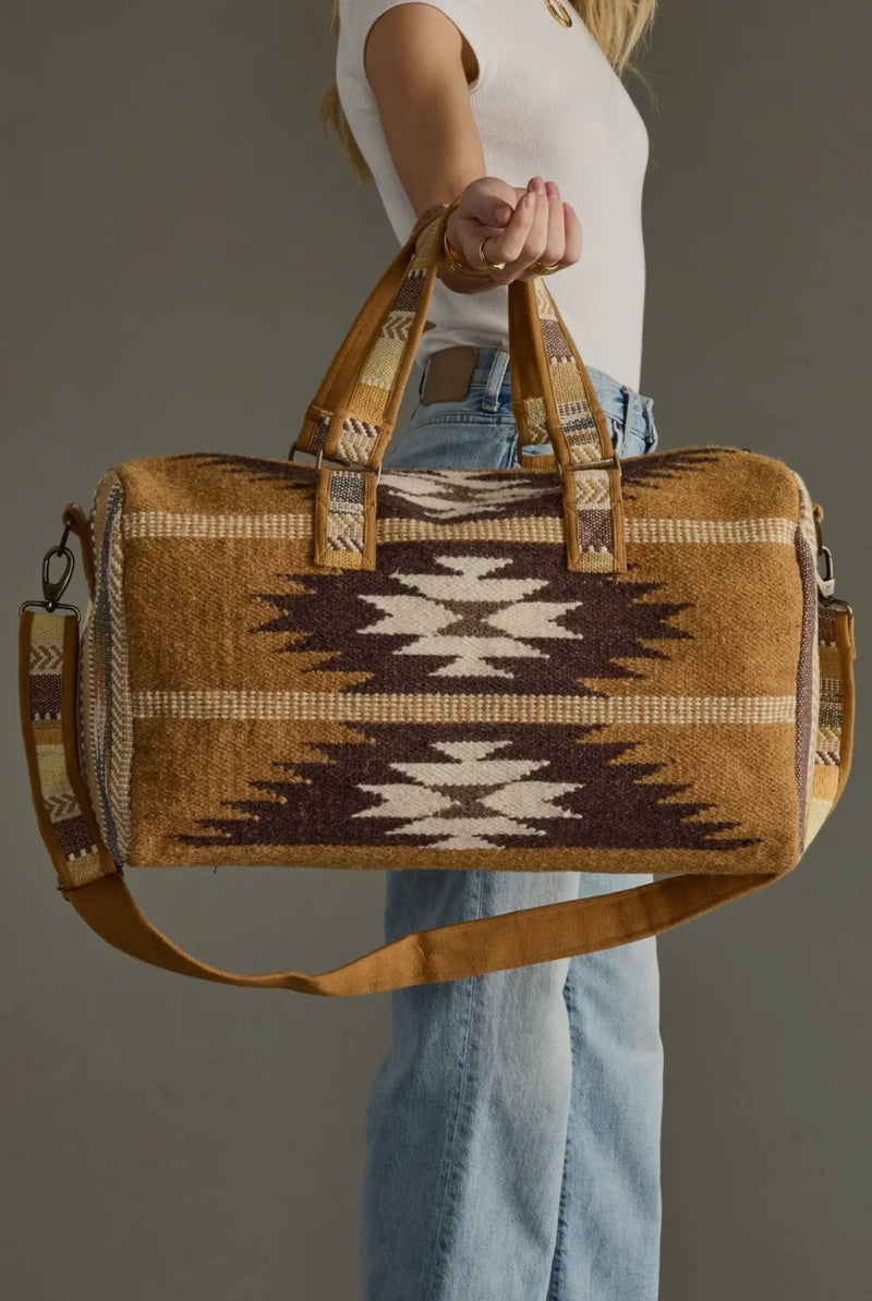 Crème, brown, and camel duffel bag